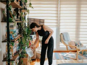 A woman watering her modern house plants with a jug of water